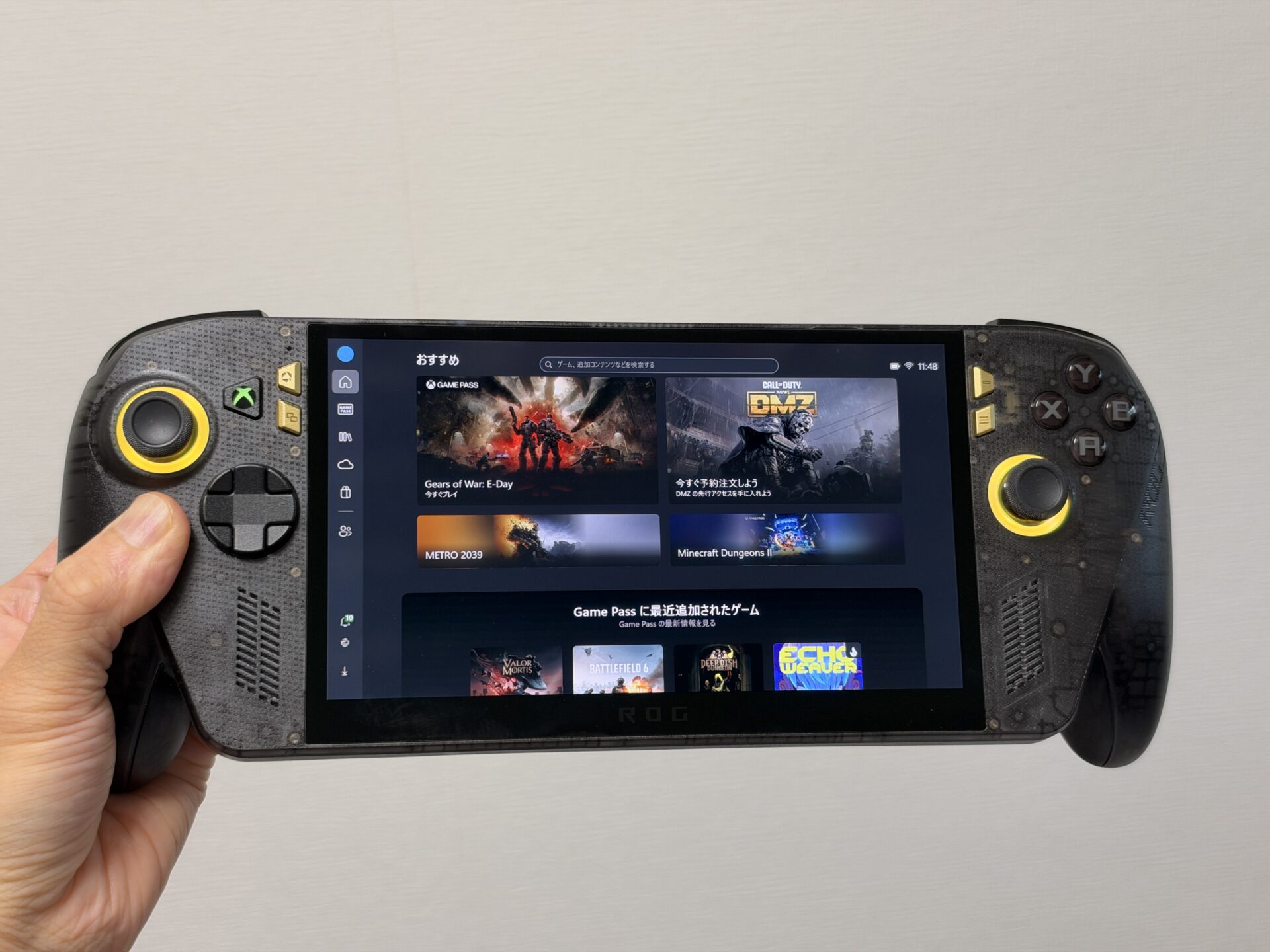 Xboxアプリを表示したROG XBOX Ally X20の正面。半透明ブラックのボディとゴールドのスティック周辺